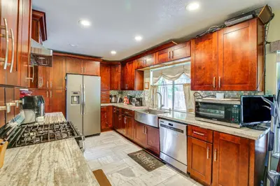a kitchen with wooden cabinets and stainless steel appliances at Anaheim Home with Pool, 14 Mi to Disneyland! in Anaheim