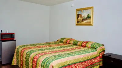 a bedroom with a bed with a colorful blanket on it at Red Carpet Motel By Ontario in Ontario