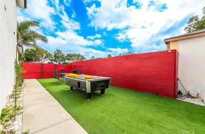 a backyard with a red fence and a grill at Cozy Haven private room 3 in Los Angeles
