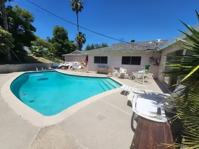 a swimming pool with two chairs and a house at Charming 5 Bedroom Granada Hills House with Pool in Los Angeles