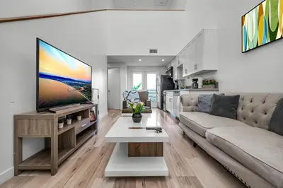 a living room with a couch and a flat screen tv at Modern 1-Bedroom Loft in Hollywood with Parking, WiFi & Hollywood Sign View in Los Angeles