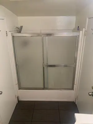 a glass shower door in a bathroom with a tile floor at LA Love Home in Los Angeles