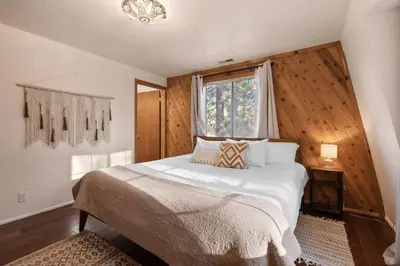 a bedroom with a large bed with a window at Hillcrest HappyNest - Hot tub, fire pit, gas grill in Big Bear Lake