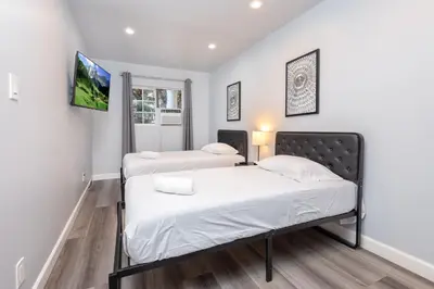 two beds in a room with white walls at Deluxe Modern 2BR Apt in Prime Location in Los Angeles