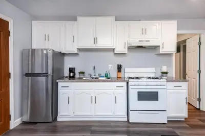 a kitchen with white cabinets and a stainless steel refrigerator at Deluxe Modern 2BR Apt in Prime Location in Los Angeles