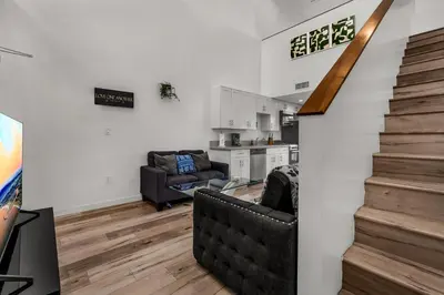 a living room with a staircase and a kitchen at Stylish Modern one Bedroom Hollywood Loft With in unite washer dryer & Balcony in Los Angeles