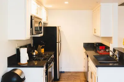 a kitchen with white cabinets and a black refrigerator at Chic Large 1 Bedroom Apartment in Koreatown with Dining Area Free Gated Parking in Los Angeles