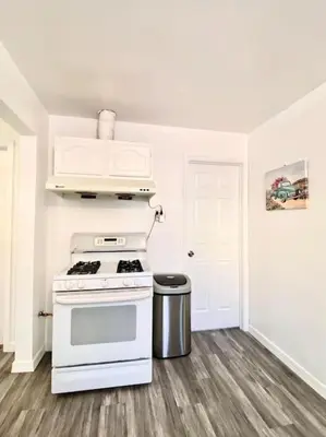 a white kitchen with a stove and a trash can at Pink Cozy house 2 bedrooms in Rosemead