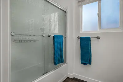 a bathroom with a glass shower with blue towels at Modern 2 Levels One-Bedroom Retreat in central Location in Hollywood in Los Angeles