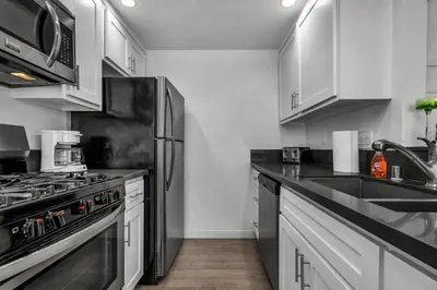 a kitchen with stainless steel appliances and white cabinets at Fully Furnished 1 Bedroom Apartment with Full Bathroom in Koreatown Free Gated Parking Full Kitchen in Los Angeles