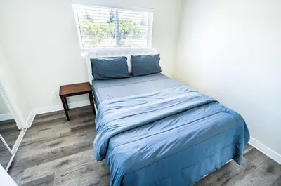 a bedroom with a bed with blue sheets and a window at Spacious 5 Bedroom 3 Bath Home for Large Groups By DT LA in Los Angeles