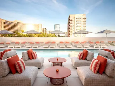 a poolside lounge with couches and tables and chairs at Fairmont Breakers Long Beach in Long Beach