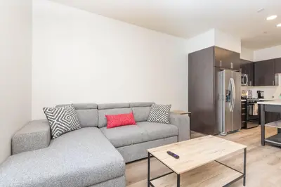 a living room with a gray couch and a kitchen at The Modern Suite Residences in Glendale