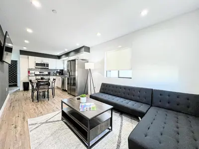 a living room with a black couch and a table at Elegant 4-Bedroom Family Home - Oak2 - LAD in Los Angeles
