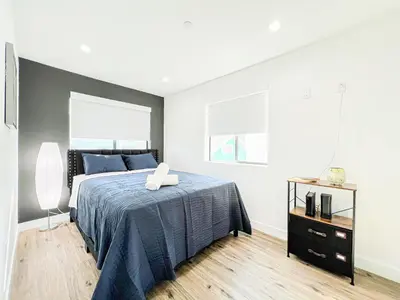 a bedroom with a bed with a blue blanket and two windows at Elegant 4-Bedroom Family Home - Oak2 - LAD in Los Angeles