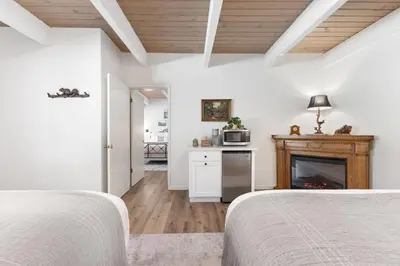 a white bedroom with two beds and a fireplace at Camp Nelson Lodge Room 2 in Ponderosa