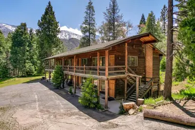 a log cabin in the woods with mountains in the background at Bear's Den @CN Lodge #5 in Ponderosa