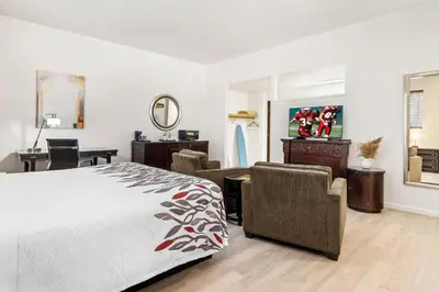 a bedroom with a bed and chairs and a desk at Red Roof Inn Ridgecrest in Ridgecrest