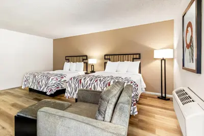a hotel room with two beds and a couch at Red Roof Inn Ridgecrest in Ridgecrest