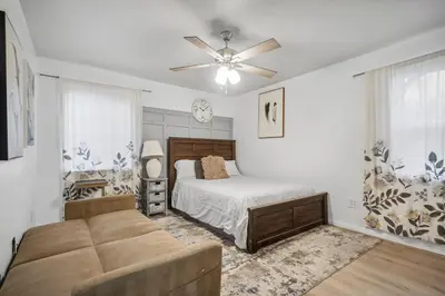 a bedroom with a bed and a couch and a ceiling fan at Cozy single story 2 bdrm family home near the BLVD in Lancaster