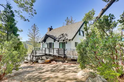 a white house with a porch in the woods at Lake Arrowhead Cabin with Hot Tub and Mountain Views! in Lake Arrowhead