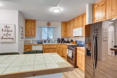 a kitchen with wooden cabinets and a stainless steel refrigerator at Crestline Home with Deck Less Than 2 Mi to Lake Gregory! in Crestline
