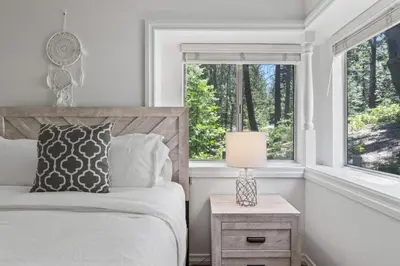 a bedroom with a bed with a lamp on a night stand at Luxe Mountain Retreat Lake Village Close Game Room AC Backs up to trails in Lake Arrowhead