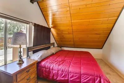 a bedroom with a red bed and a wooden ceiling at Frazier Park Cabin with Ping-Pong Table, Near Trails in Frazier Park
