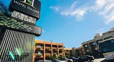 a sign for a hotel with cars parked in a parking lot at Hotel Solaire Los Angeles in Los Angeles