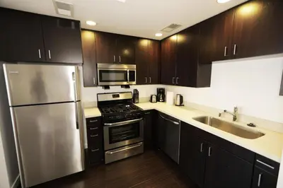 a kitchen with stainless steel appliances and wooden cabinets at Downtown Cosmopolitan Residences in Los Angeles