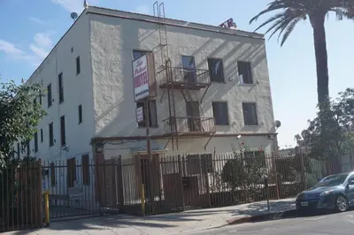 a white building with a fence in front of it at Las Palmas Hotel in Los Angeles