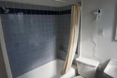 a bathroom with a blue tiled shower and a toilet at Las Palmas Hotel in Los Angeles