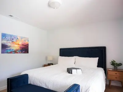 a bedroom with a large bed with a blue chair at Family Renovated Home, Netflix, AC, WD, Putt Putt in Fullerton