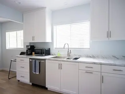 a white kitchen with a sink and a microwave at Family Renovated Home, Netflix, AC, WD, Putt Putt in Fullerton