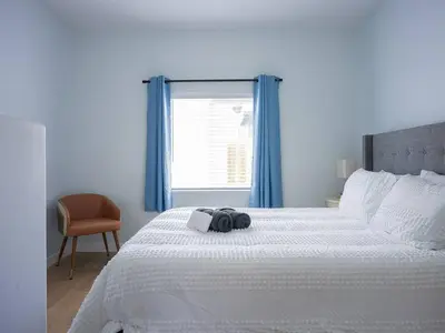 a bedroom with a large white bed and a window at Family Renovated Home, Netflix, AC, WD, Putt Putt in Fullerton
