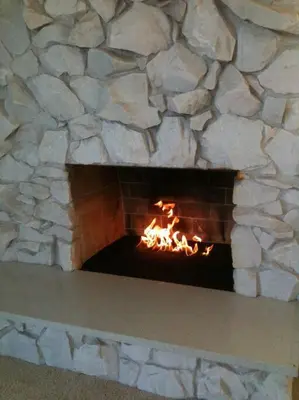 a stone fireplace with a fire in it at Luxe in Hollywood Hills- modern oasis, pool 5 min to Sunset in Los Angeles