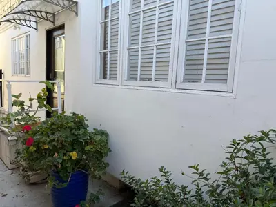 a white house with a window and a potted plant at Pasadena Old Town Cottage in Pasadena