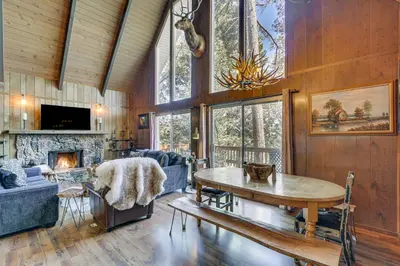 a living room with a table and a fireplace at Chic Lake Arrowhead Retreat 4 Seasons of Fun! in Lake Arrowhead