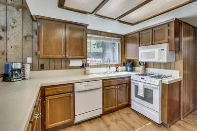 a kitchen with wooden cabinets and white appliances at Chic Lake Arrowhead Retreat 4 Seasons of Fun! in Lake Arrowhead