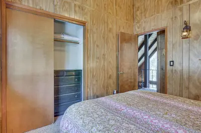 a bedroom with a bed and a wooden wall at Chic Lake Arrowhead Retreat 4 Seasons of Fun! in Lake Arrowhead