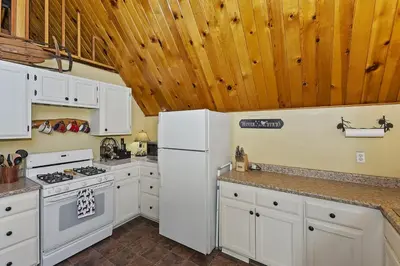 a kitchen with white appliances and wooden ceilings at Lake Arrowhead Charming Chalet in Lake Arrowhead