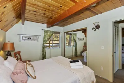 a bedroom with a white bed with a wooden ceiling at Lake Arrowhead Charming Chalet in Lake Arrowhead