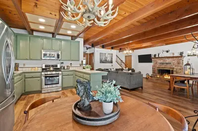 a kitchen and living room with green cabinets and a table at Big Bear Lake Sleep 16 in Big Bear Lake