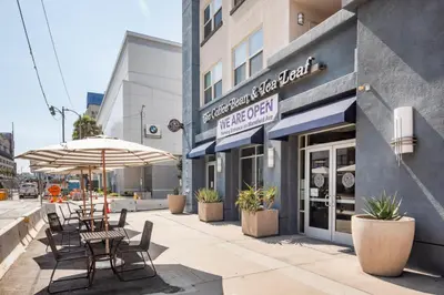 an outdoor patio with tables and chairs and an umbrella at Blueground Mid-Wilshire pool near The Grove LAX-1223 in Los Angeles
