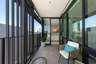 a balcony with glass walls and a chair at The Sapphire Nest - Spectacular Rooftop Amenities Ocean views 2BR in Los Angeles