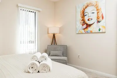 a bedroom with a bed and a chair and a painting at Luxury One Bedroom minutes from The Grove in Los Angeles