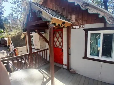 a house with a red door on a balcony at Big Bear Lake - Tulip Lane Cabin #22 in Big Bear Lake
