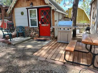 a house with a red door and a stove at Big Bear Lake - Tulip Lane Cabin #23 - Micro Cabin in Big Bear Lake