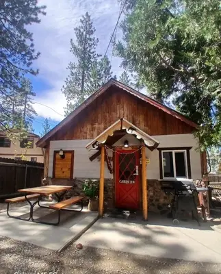 a cabin with a red door and a picnic table at Big Bear Lake - Tulip Lane Cabin #24 in Big Bear Lake