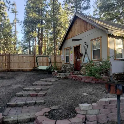 a small house in the woods with a fence at Big Bear Lake - Tulip Lane Cabin #26 in Big Bear Lake